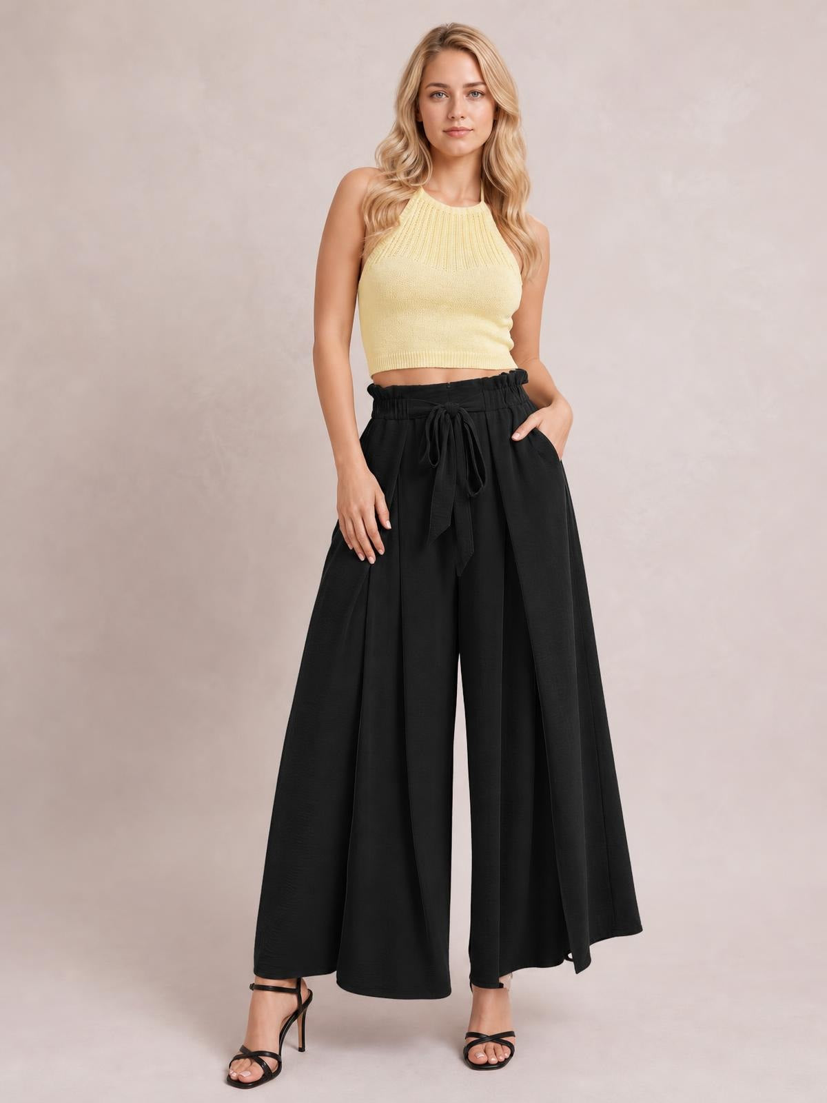 A model poses in black opaque tied slit wide-leg pants with a high waist, flowing silhouette, and hands resting near the pockets.