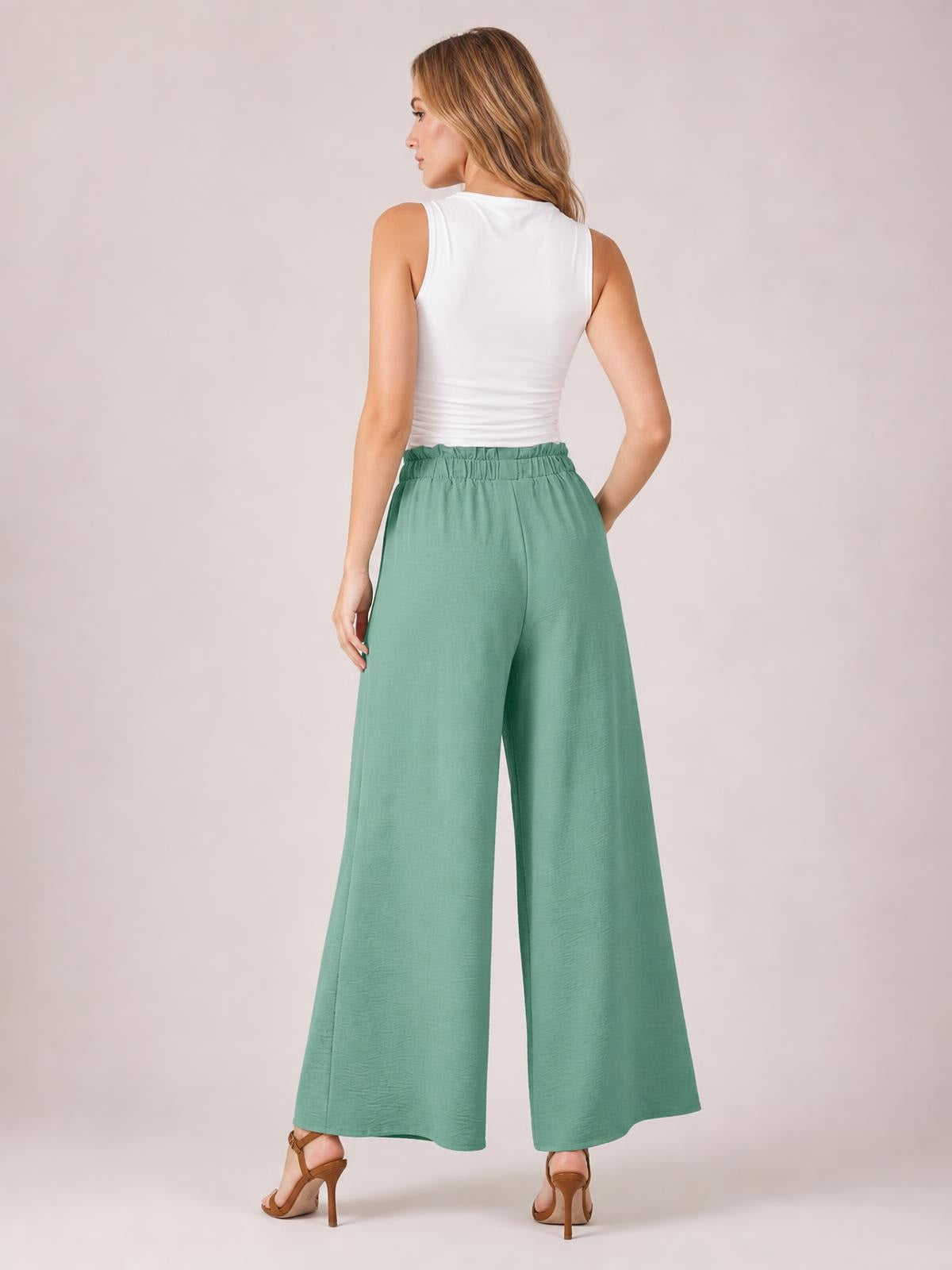 Model poses from behind in mint green tied slit wide-leg pants with a gathered elastic waistband and flowing full-length silhouette.