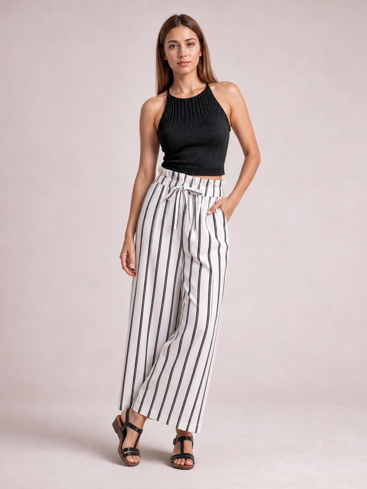 Model poses in white striped wide-leg pants with a tied drawstring waist, elastic waistband, relaxed flowy silhouette, and side pockets.