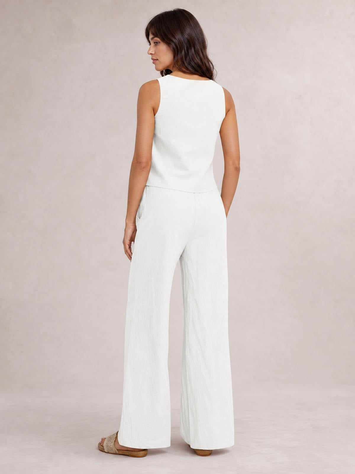 Model shown from behind in a white sleeveless top and matching drawstring pants set, featuring a clean silhouette, wide-leg cut, and hand in a pocket.