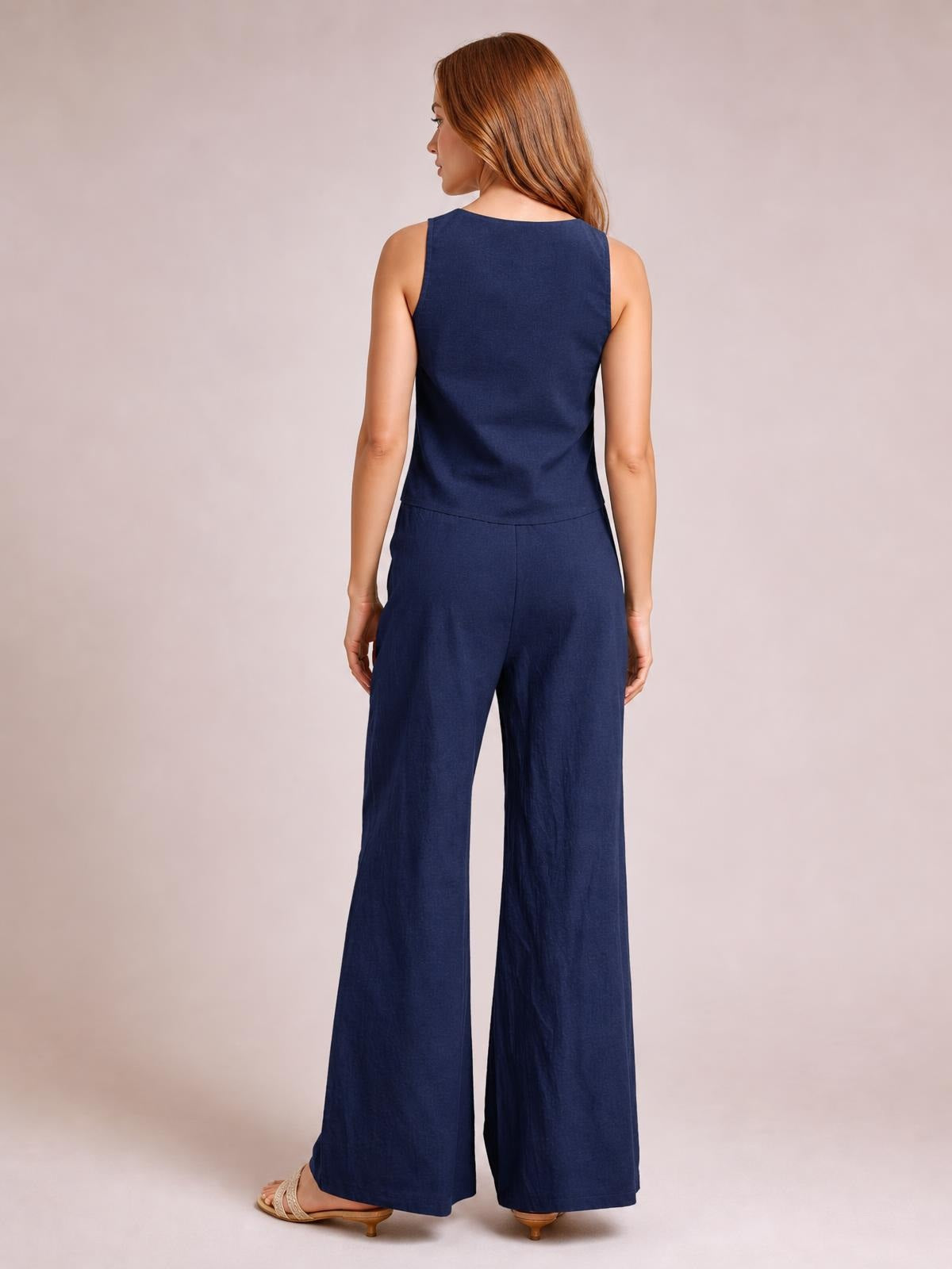 A model stands in a navy tied V-neck sleeveless top and matching wide-leg pants set, shown from the back in a relaxed silhouette.