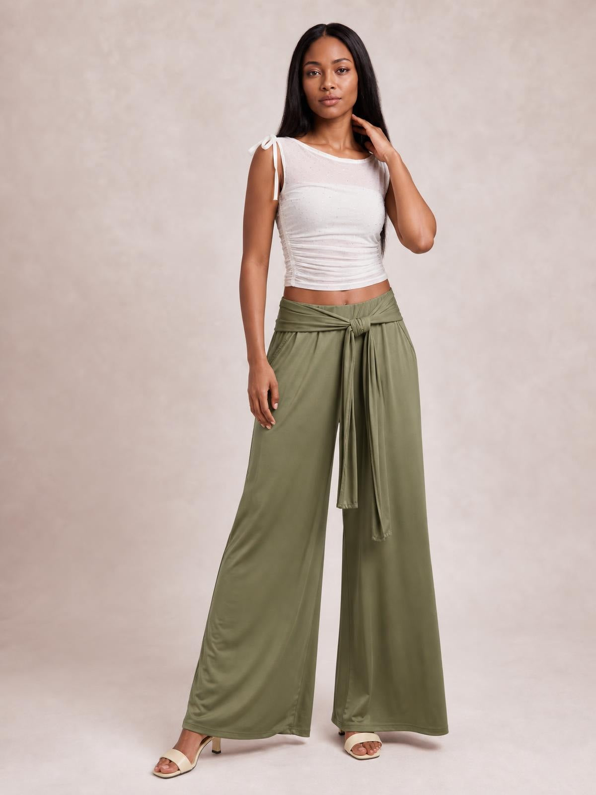 Model poses in olive green tied wide-leg pants with a high waist, flowing full-length silhouette, and visible front tie detail.