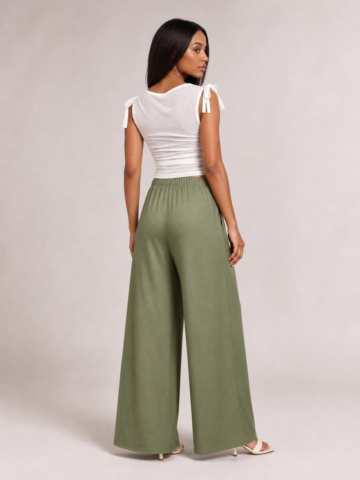 Model shown from the back wears olive green tied wide-leg pants with a gathered waistband, relaxed flowing silhouette, and side pockets.