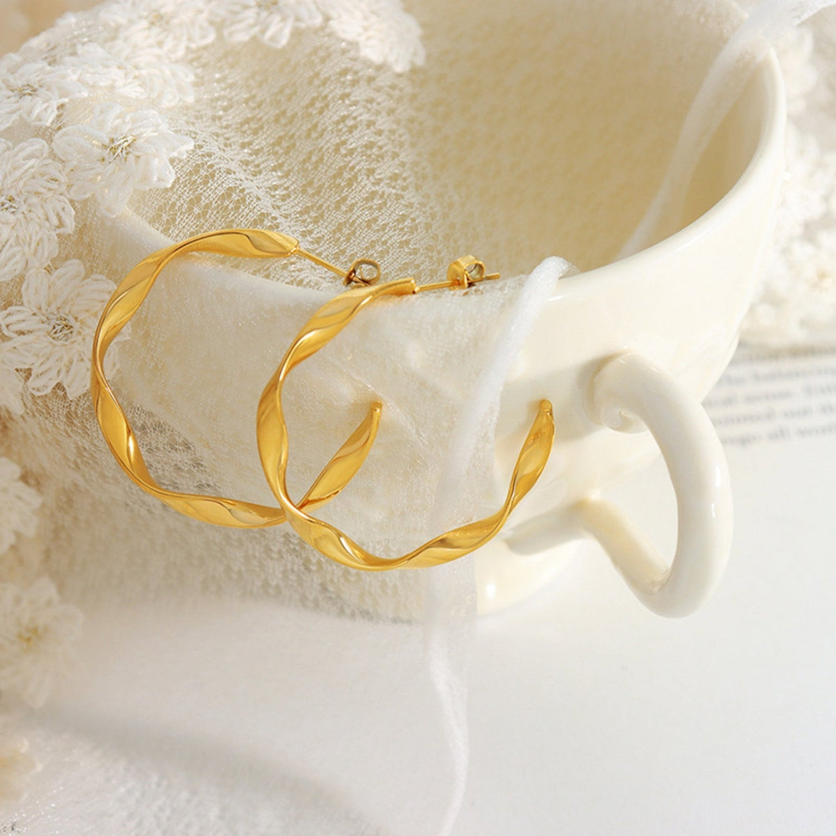 Gold-plated titanium steel C-hoop earrings feature a polished curved silhouette with subtly twisted bands and secure post closures.