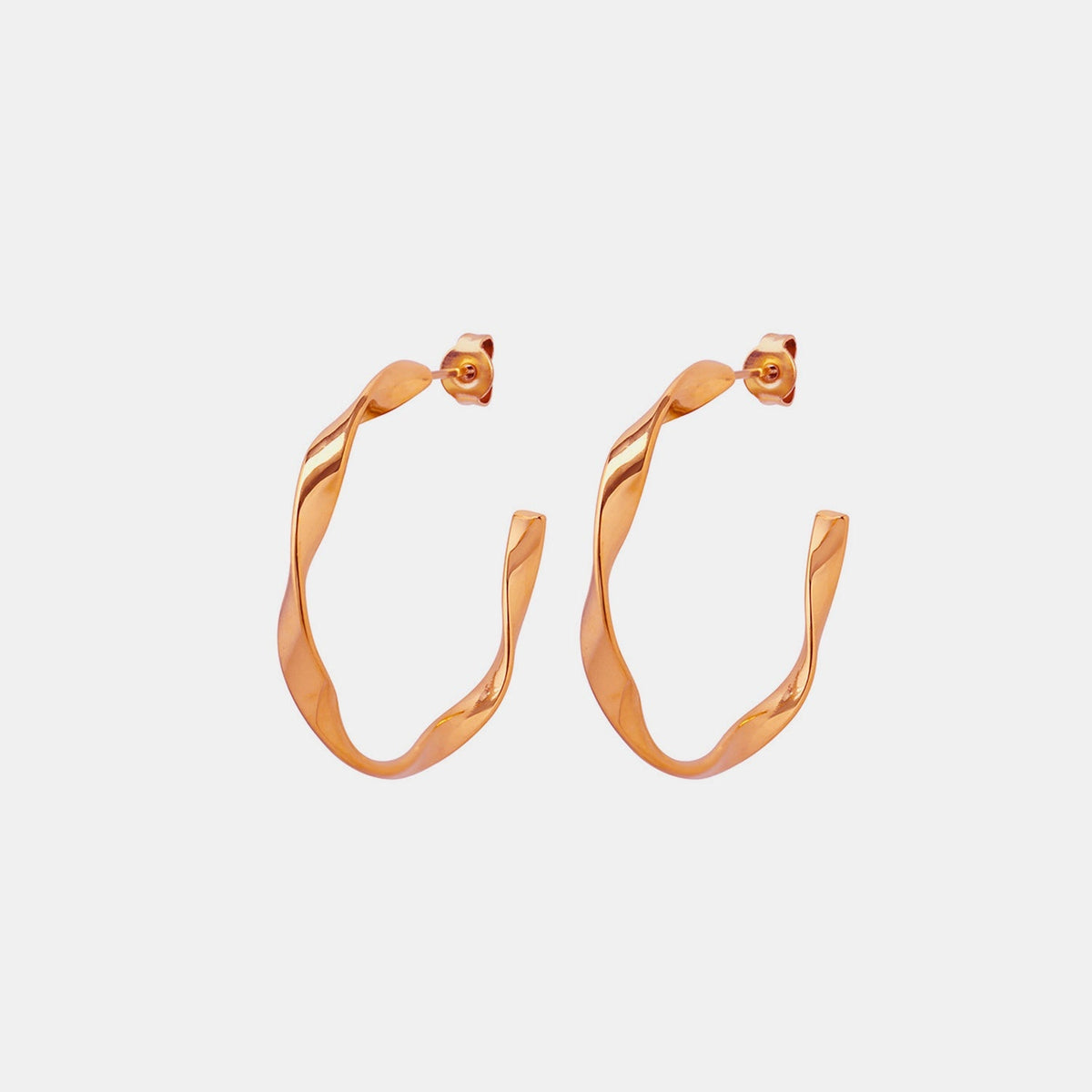Polished gold-plated titanium steel C-hoop earrings feature an elongated curved silhouette, sculptural twisted construction, and secure post-back closures.