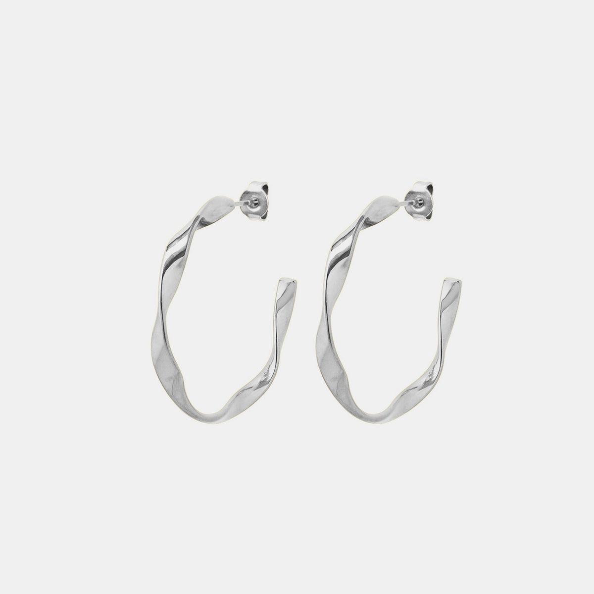 Polished silver-tone titanium steel C-hoop earrings feature a sculptural, gently twisted open silhouette with smooth tapered bands and post backs.