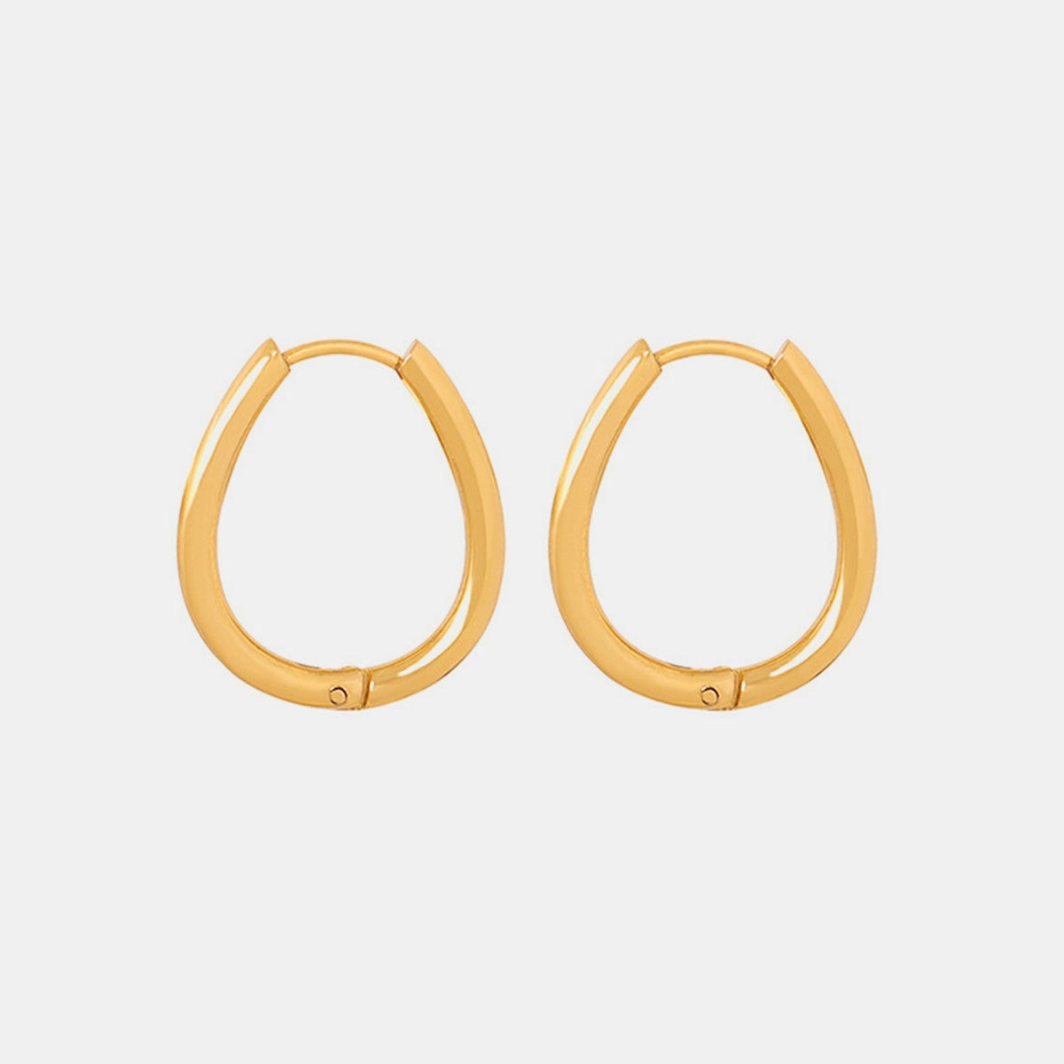 Pair of gold-toned titanium steel huggie earrings with smooth rounded hoops, compact silhouettes, and hinged latch closures.