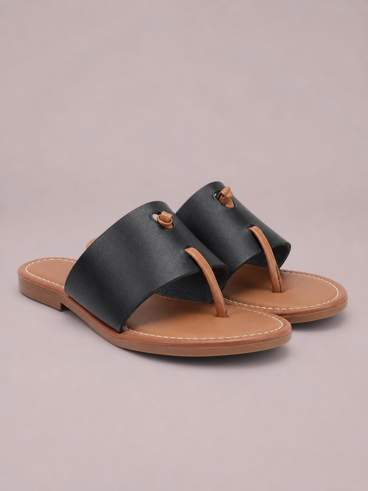 Black toe post flat sandals with wide PU leather straps, tan footbeds, stitched edges, and low rubber soles.