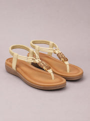 Beige toe post flat sandals feature woven ankle straps, decorative braided detailing, tan footbeds, and low rubber soles.