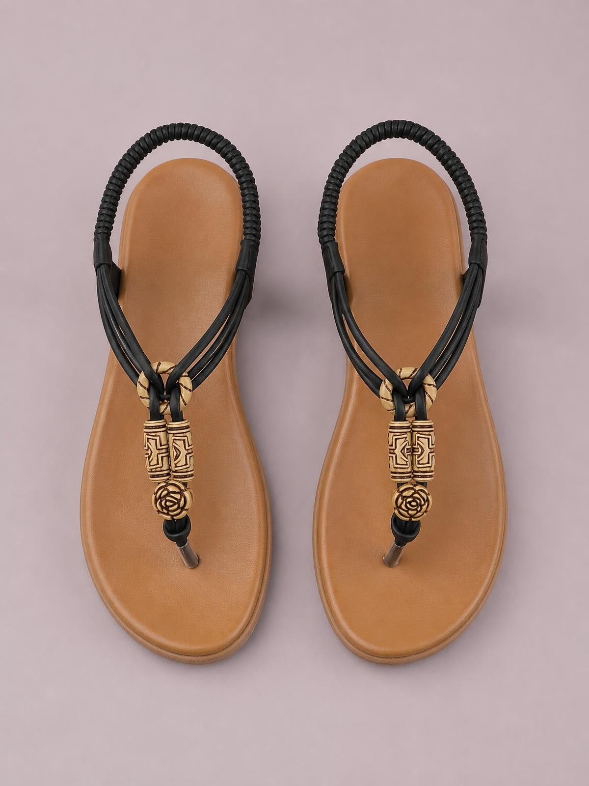 Tan flat toe post sandals with black PU leather straps, rounded soles, and decorative geometric beads and rosette accents at the front.