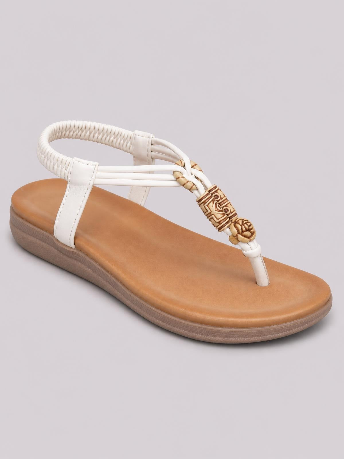 White toe post flat sandal with a tan footbed, braided ankle strap, decorative woven accent, and low rubber sole.