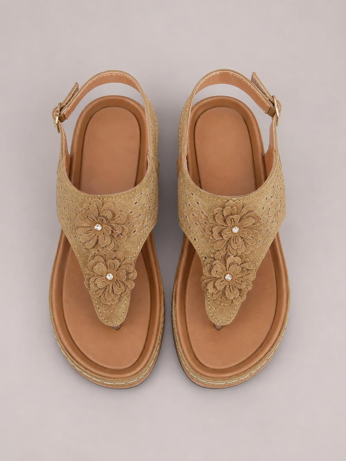 Tan toe post wedge sandals feature floral cutout straps with jeweled flower centers, cushioned footbeds, stitched soles, and adjustable ankle buckles.