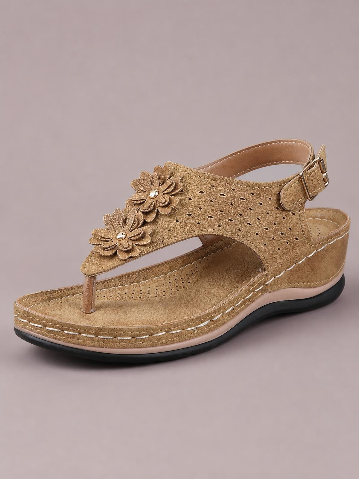 Tan toe post flower detail wedge sandal with layered floral embellishments, perforated straps, ankle buckle, stitched platform sole, and mid-height wedge heel.