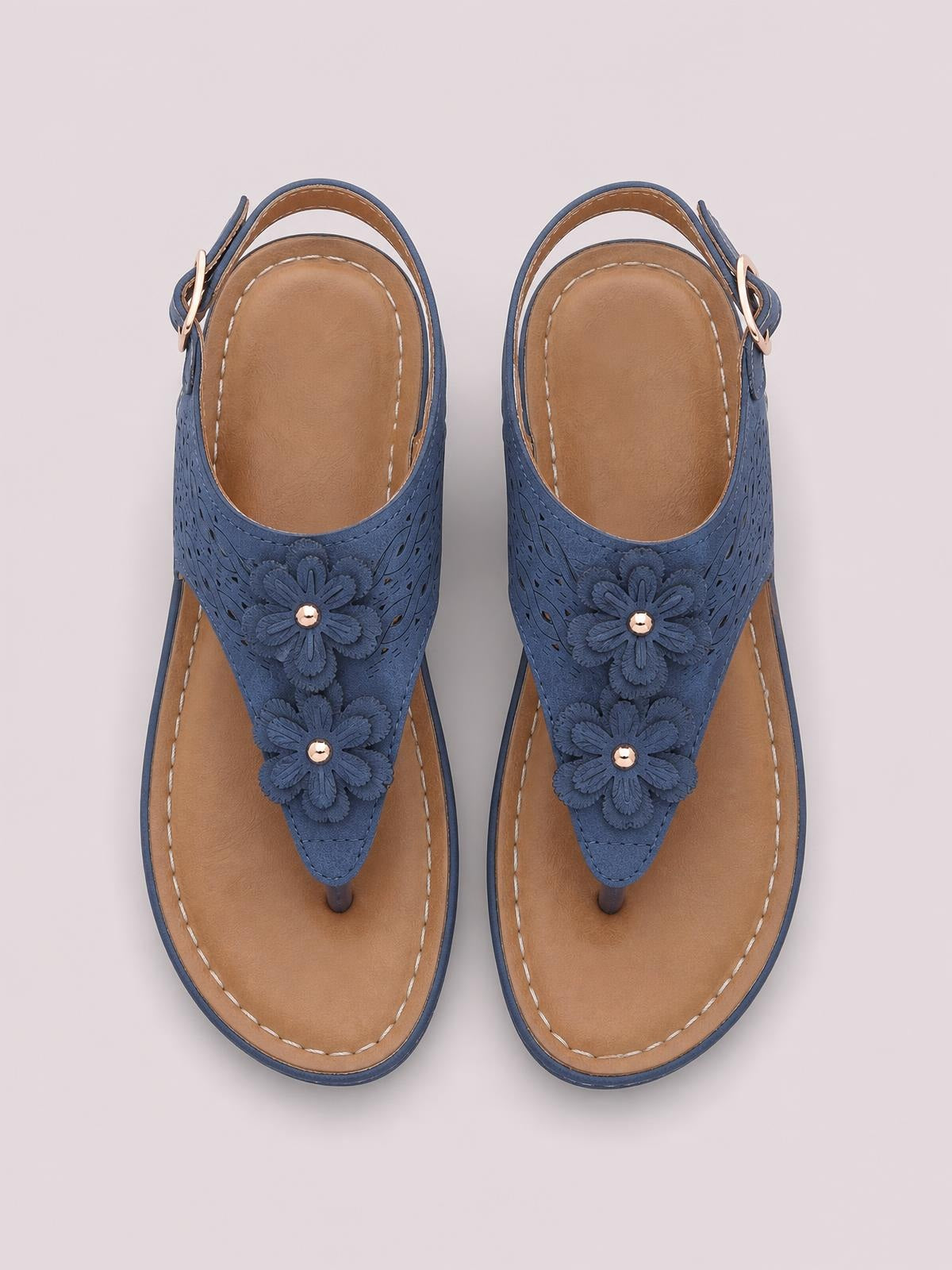 Blue toe post wedge sandals feature layered flower details, textured PU leather straps, tan cushioned footbeds, contrast stitching, and side buckles.