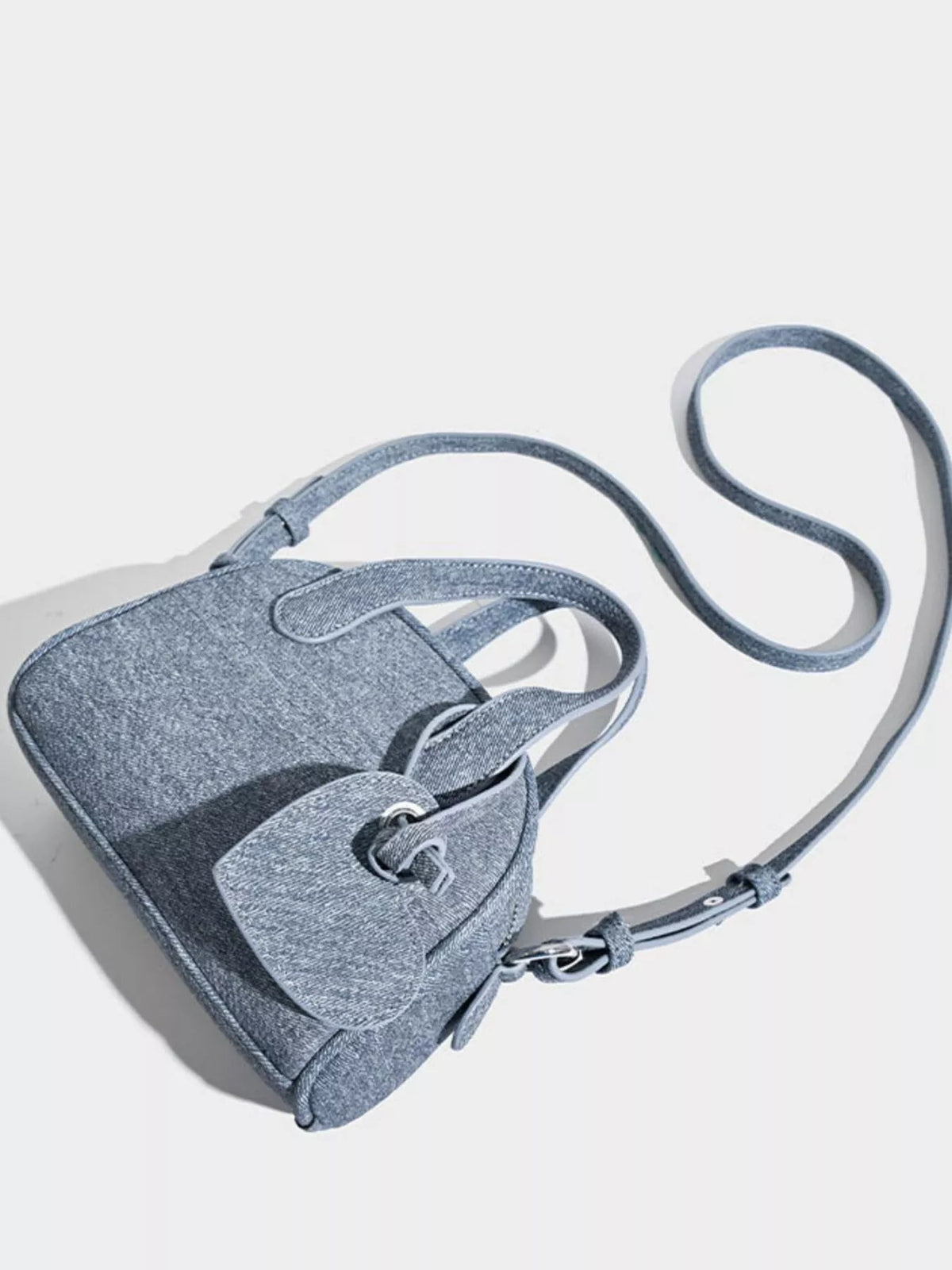 Gray mini canvas crossbody bag with a structured silhouette, top handle, flap closure, and long adjustable strap with metal hardware.