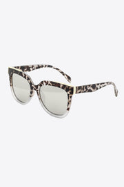 Full-rim square sunglasses feature a softly rounded light gray tortoiseshell polycarbonate frame, patterned temples, and subtly tinted gray lenses.