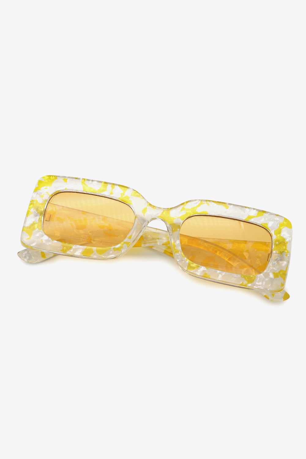 Clear yellow-and-white marbled polycarbonate rectangle sunglasses feature oversized frames, amber lenses, and a structured bridge with angled temples.