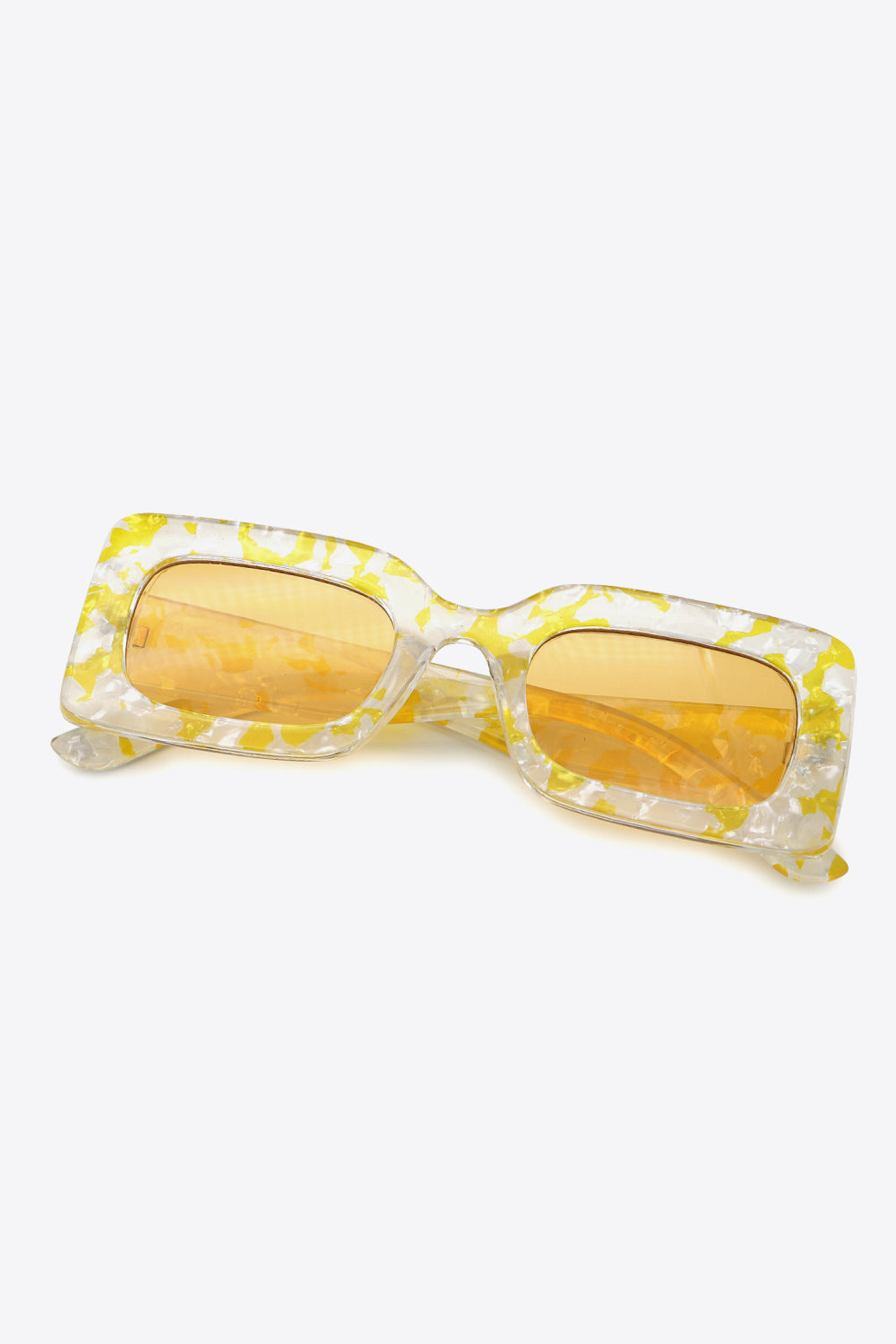 Clear yellow-and-white marbled polycarbonate rectangle sunglasses feature oversized frames, amber lenses, and a structured bridge with angled temples.