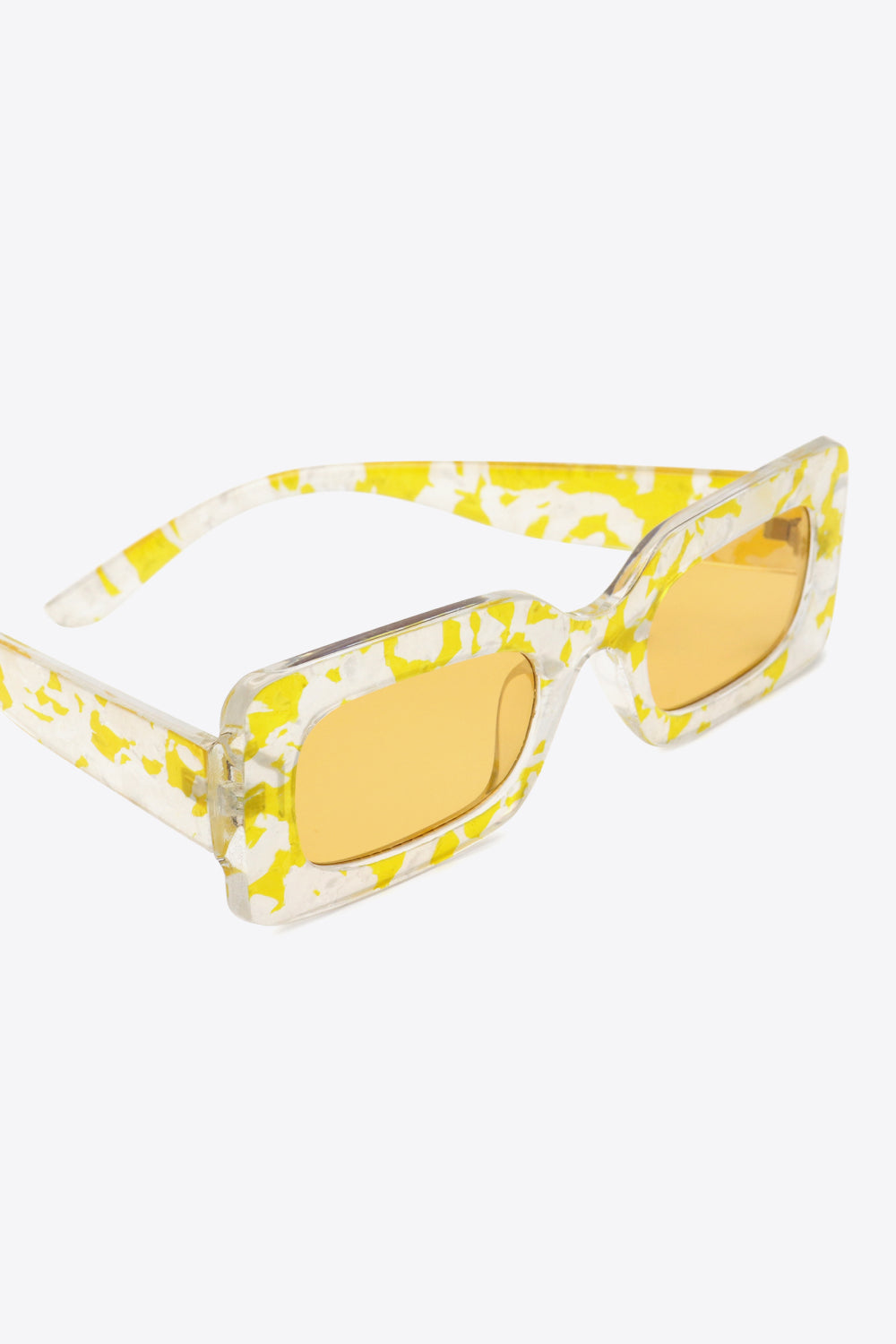 Clear and yellow marbled polycarbonate rectangle sunglasses feature a bold structured frame, amber lenses, and wide temples.