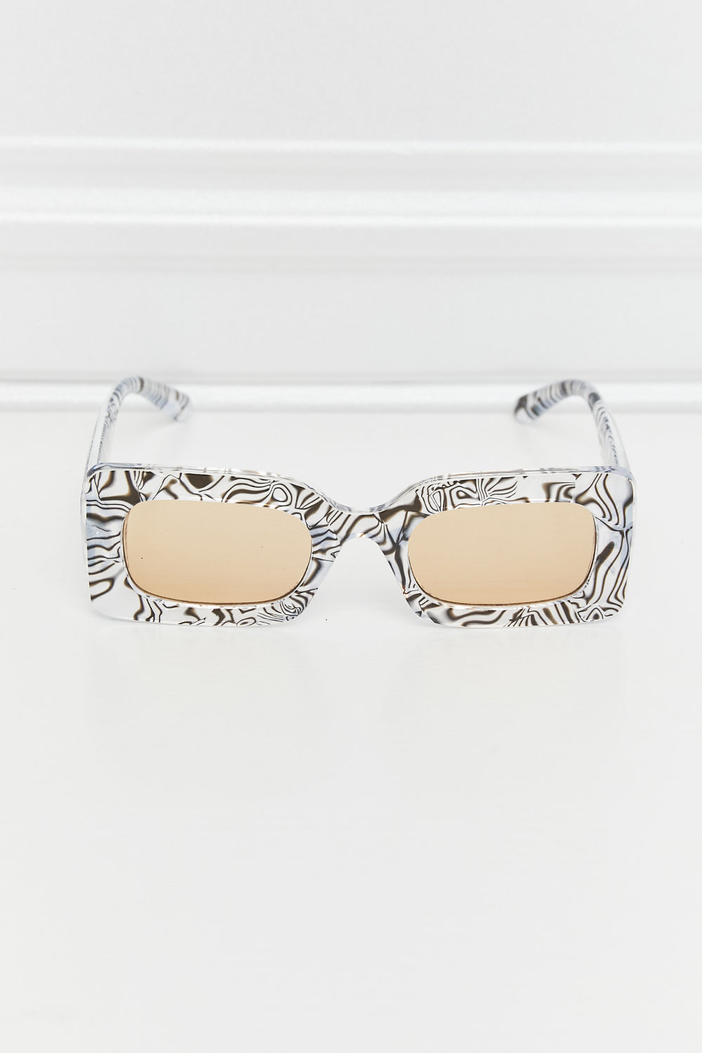 Tortoiseshell-patterned rectangle sunglasses feature a structured polycarbonate frame, beige lenses, rounded corners, and slim temples.