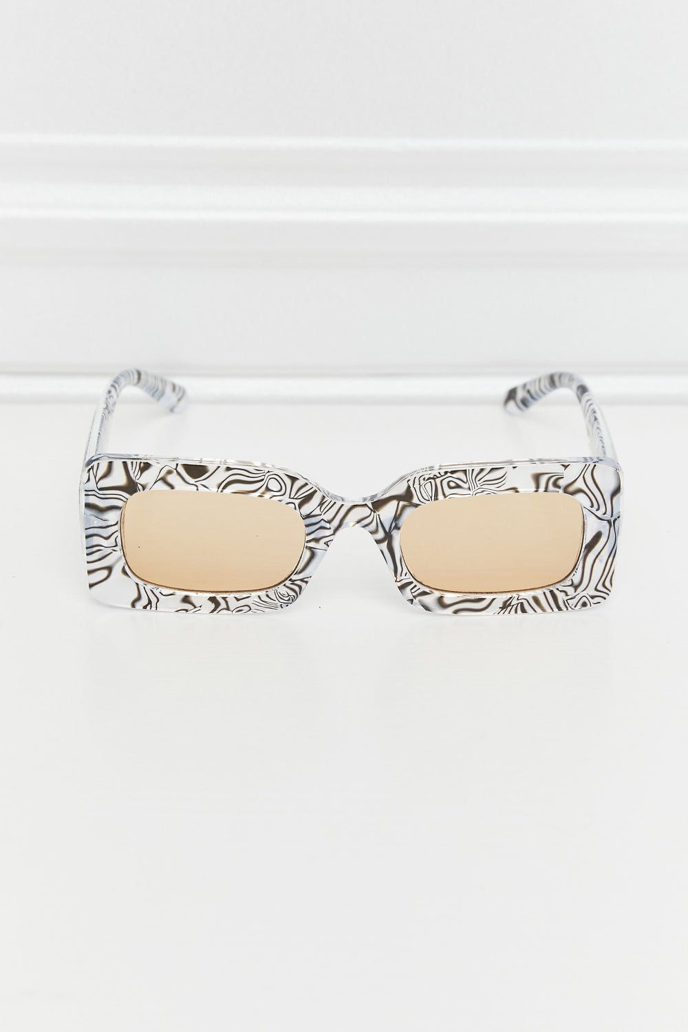 Tortoiseshell-patterned rectangle sunglasses feature a structured polycarbonate frame, beige lenses, rounded corners, and slim temples.