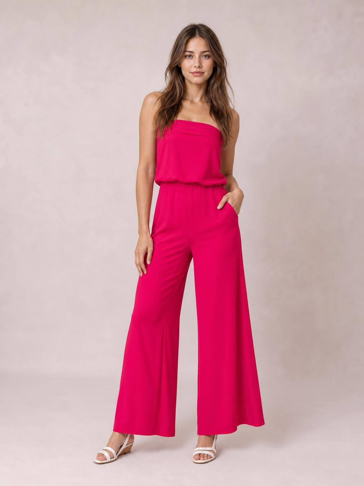 Model poses in a hot pink strapless tube top and matching wide-leg pants set with a flowing silhouette and practical side pockets.