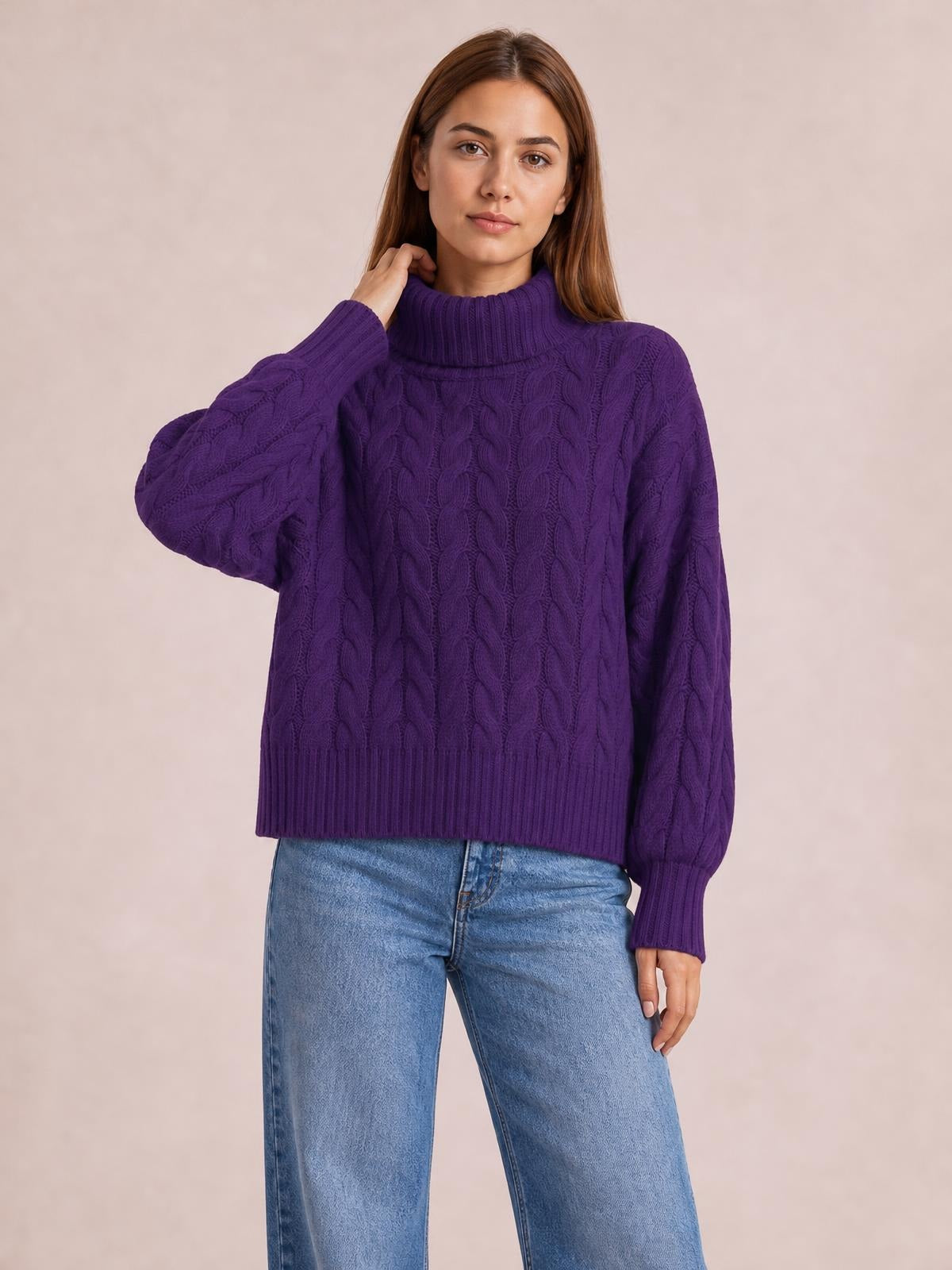 Model wearing a solid purple cable-knit turtleneck sweater with long sleeves, ribbed cuffs and hem, and a relaxed regular-length silhouette.