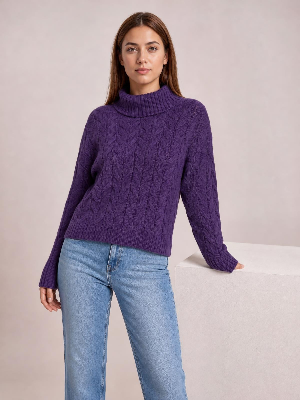 Model poses in a purple cable-knit turtleneck sweater with long regular sleeves, ribbed cuffs and hem, and a regular-length silhouette.