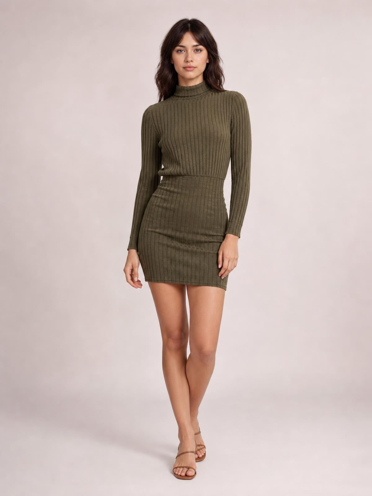 Model in a fitted olive-green ribbed knit dress with a turtleneck, long sleeves, defined waist, and short bodycon silhouette, standing with crossed legs.