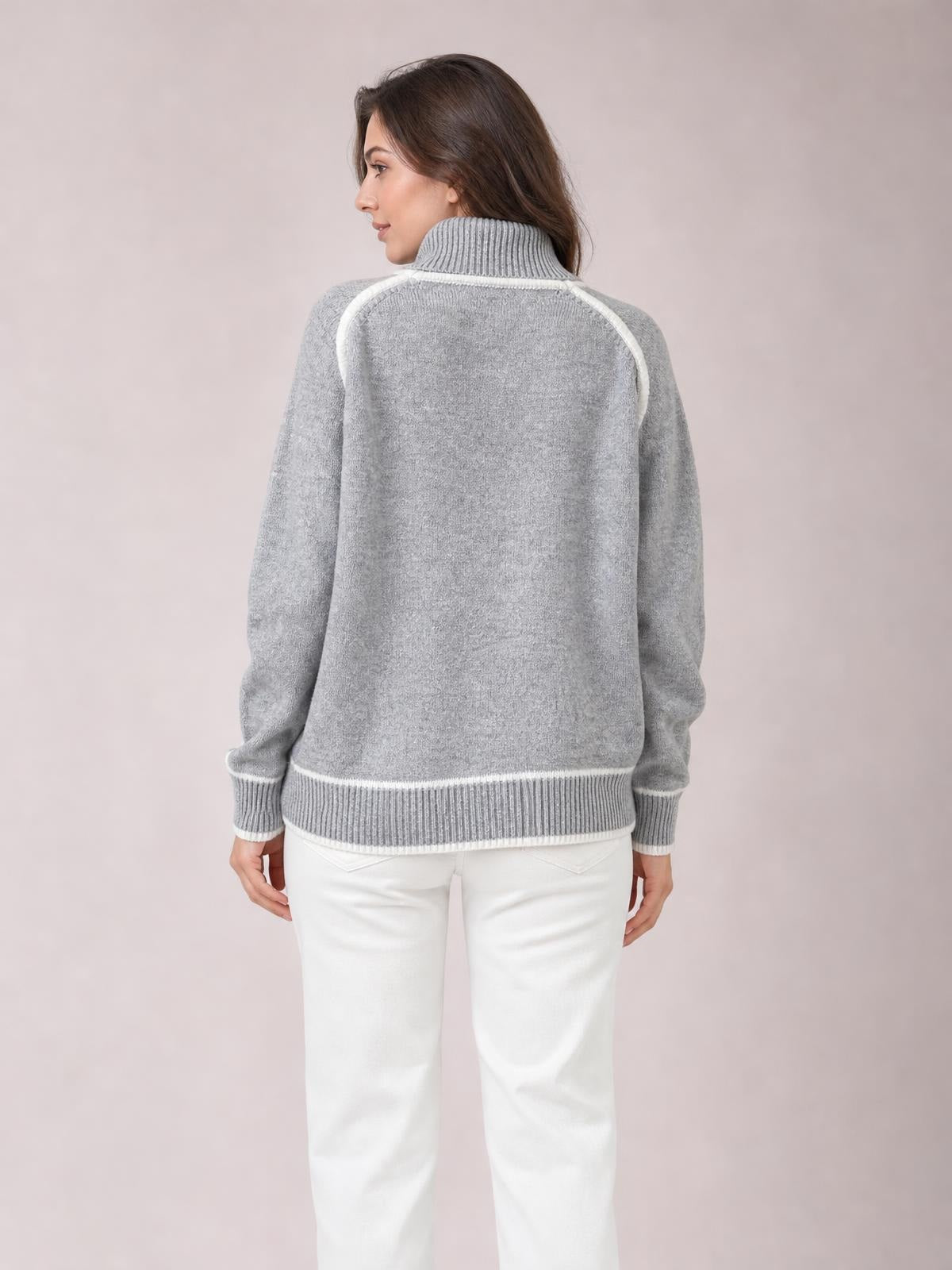 Woman viewed from behind wearing a gray turtleneck sweater with white contrast trim, ribbed collar, cuffs, and hem in a relaxed silhouette.