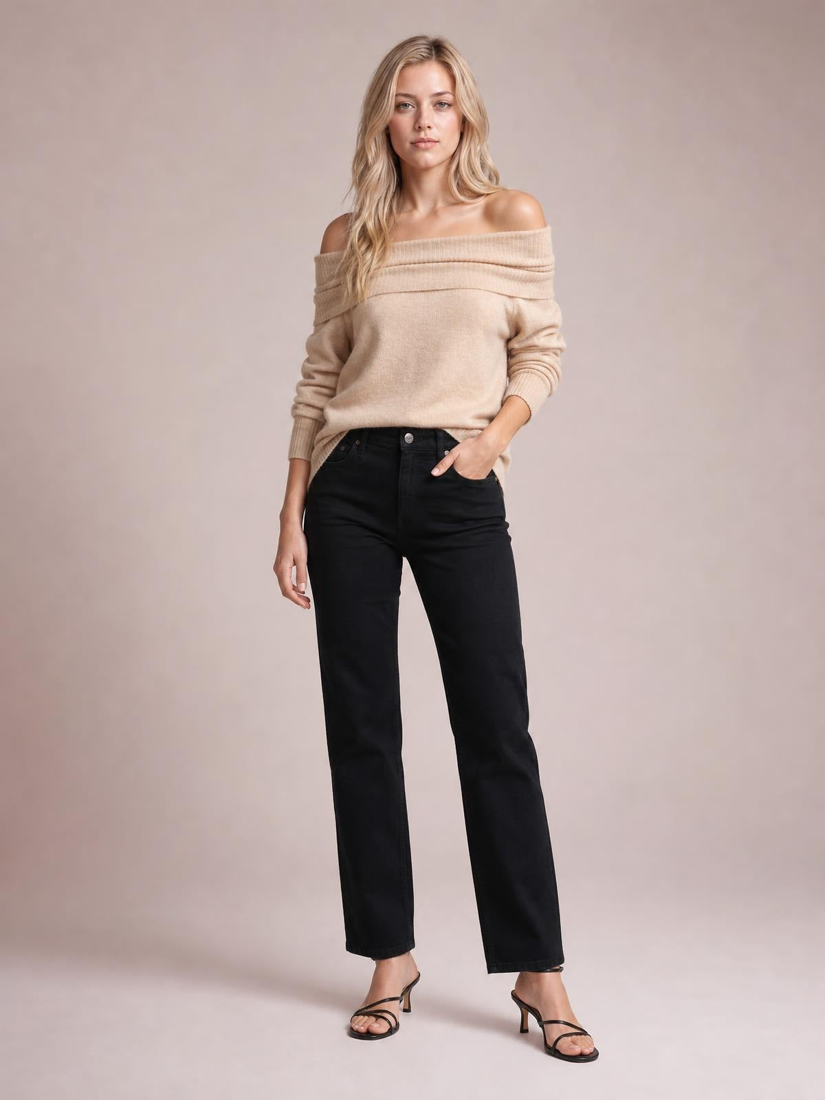 A model poses in a beige long-sleeve sweater with a wide folded off-shoulder neckline, relaxed silhouette, and ribbed cuffs, paired with black jeans.