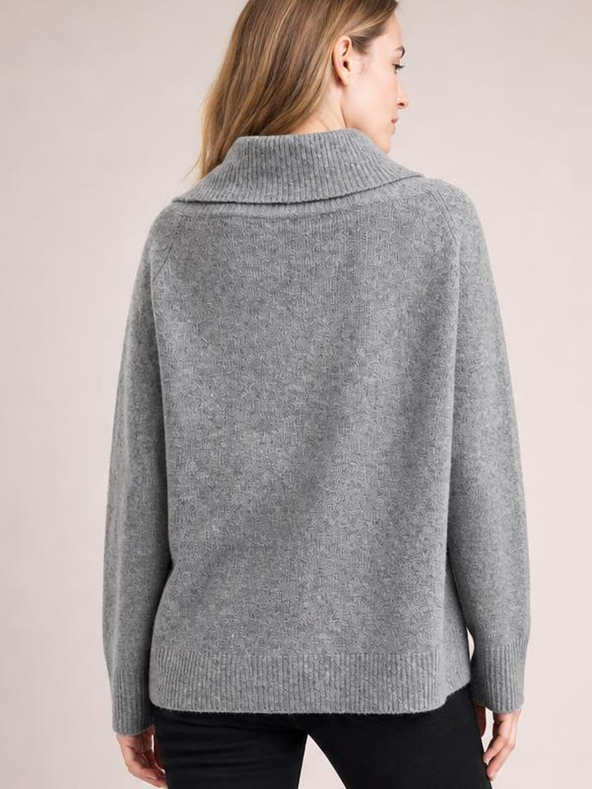 A model stands facing away in a gray turtleneck long sleeve sweater with a wide ribbed collar, ribbed cuffs and hem, and a relaxed straight silhouette.