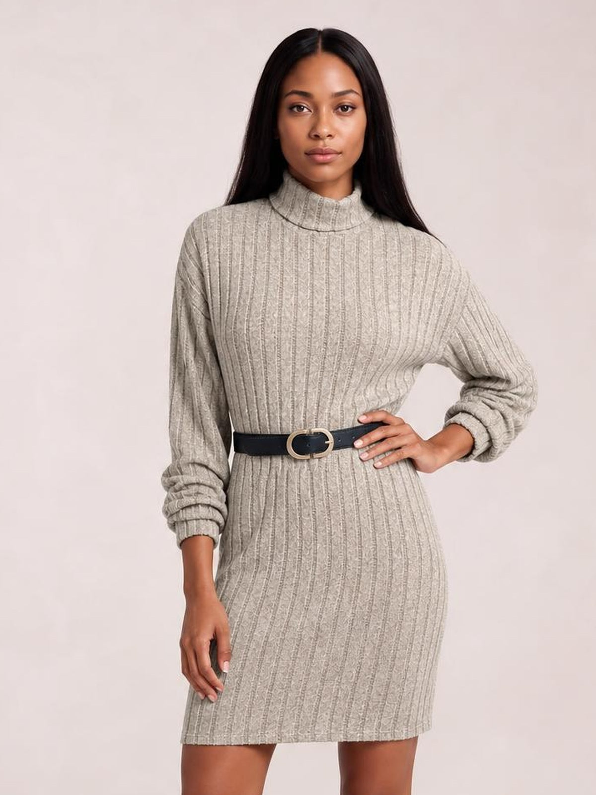 Model poses with one hand on her hip in a taupe ribbed knit dress featuring a turtleneck, long sleeves, and a straight above-knee silhouette.