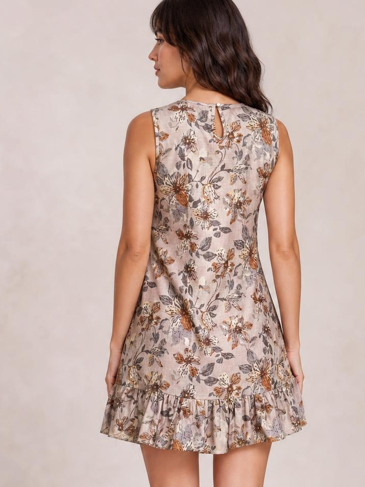 Model shown from the back in a sleeveless pale pink floral mini dress with an A-line silhouette, keyhole back closure, and gathered ruffle hem.