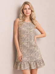 Model poses with one hand on her hip wearing a beige tweed sleeveless mini dress with a straight silhouette and flared ruffle hem.