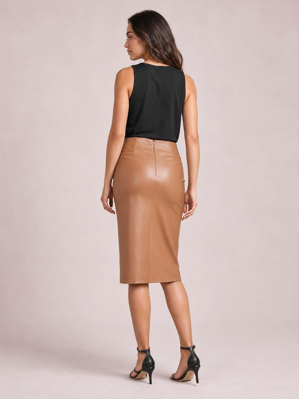 A model poses facing away in a tan Twist Detail high waist skirt with a fitted midi silhouette, back zipper, center seam, and hands at her sides.