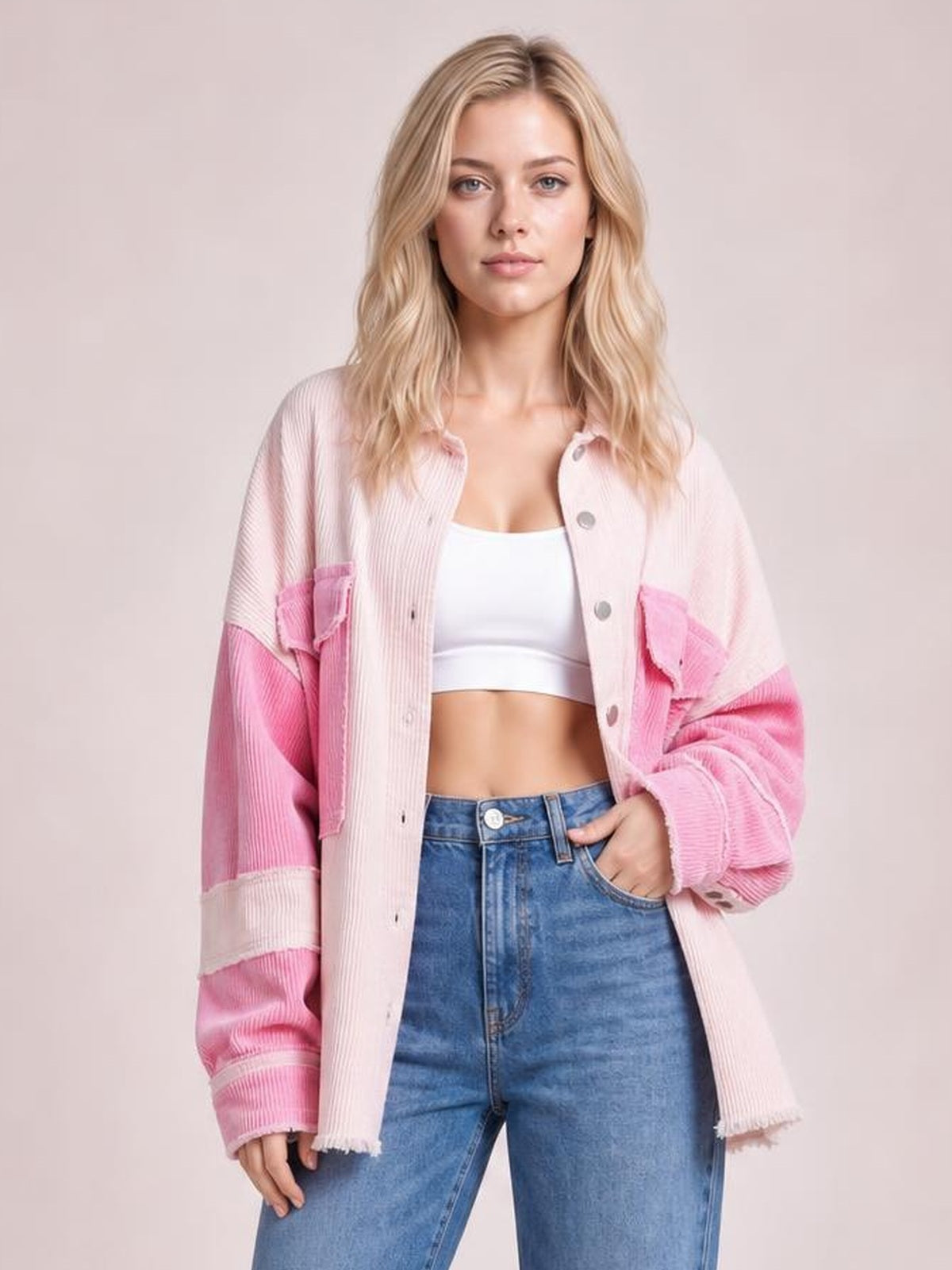 Front-facing model wears a two-tone pink corduroy shacket with exposed seams, button front, patch pockets, oversized sleeves, and a raw hem.