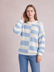 Model wearing a relaxed two-tone dropped shoulder sweater in blue and cream with a ribbed crew neck, cuffs, hem, and long sleeves.