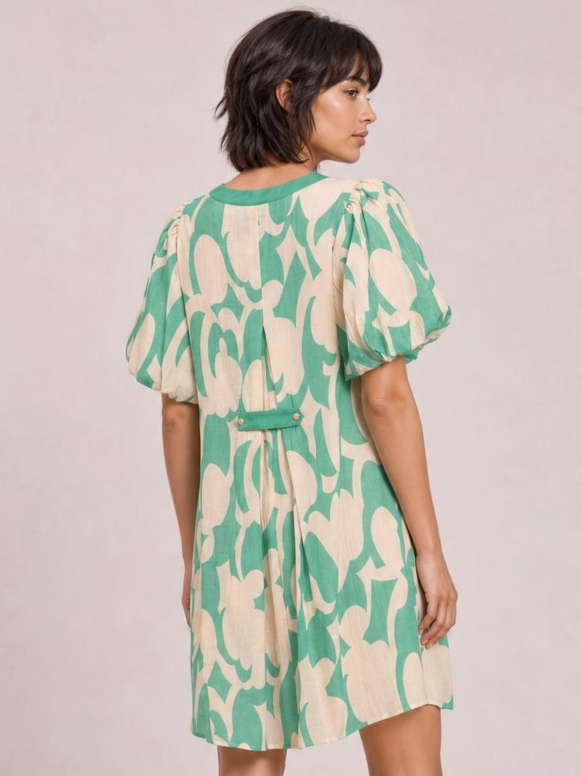 Model shown from behind wearing a mint green and beige abstract floral print shift dress with puff sleeves, a relaxed mini silhouette, and back waist tab.