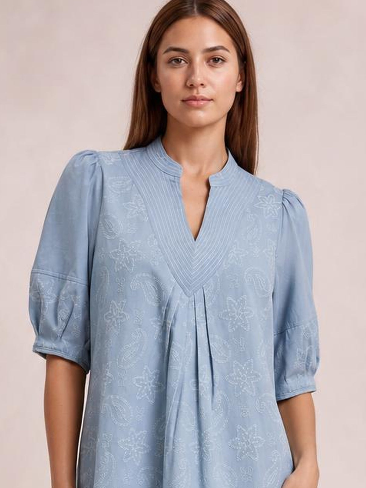 Model wears a light blue printed denim dress with a split V-neck, pintuck collar, pleated front, contrast stitching, elbow-length puff sleeves, and a relaxed silhouette.