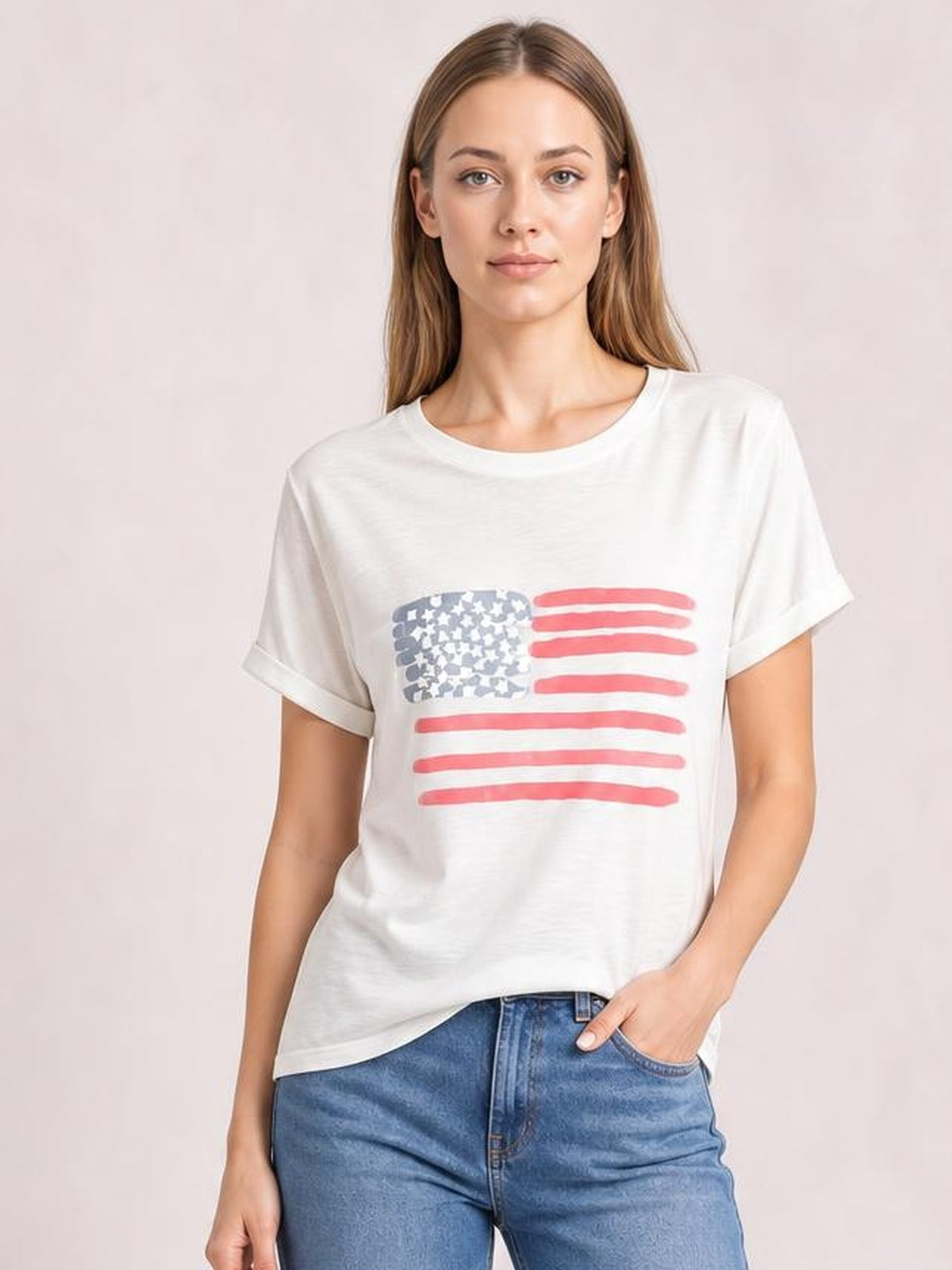 Model wearing a white US flag round neck short sleeve T-shirt with a relaxed silhouette, rolled sleeve cuffs, and red and blue flag graphic.