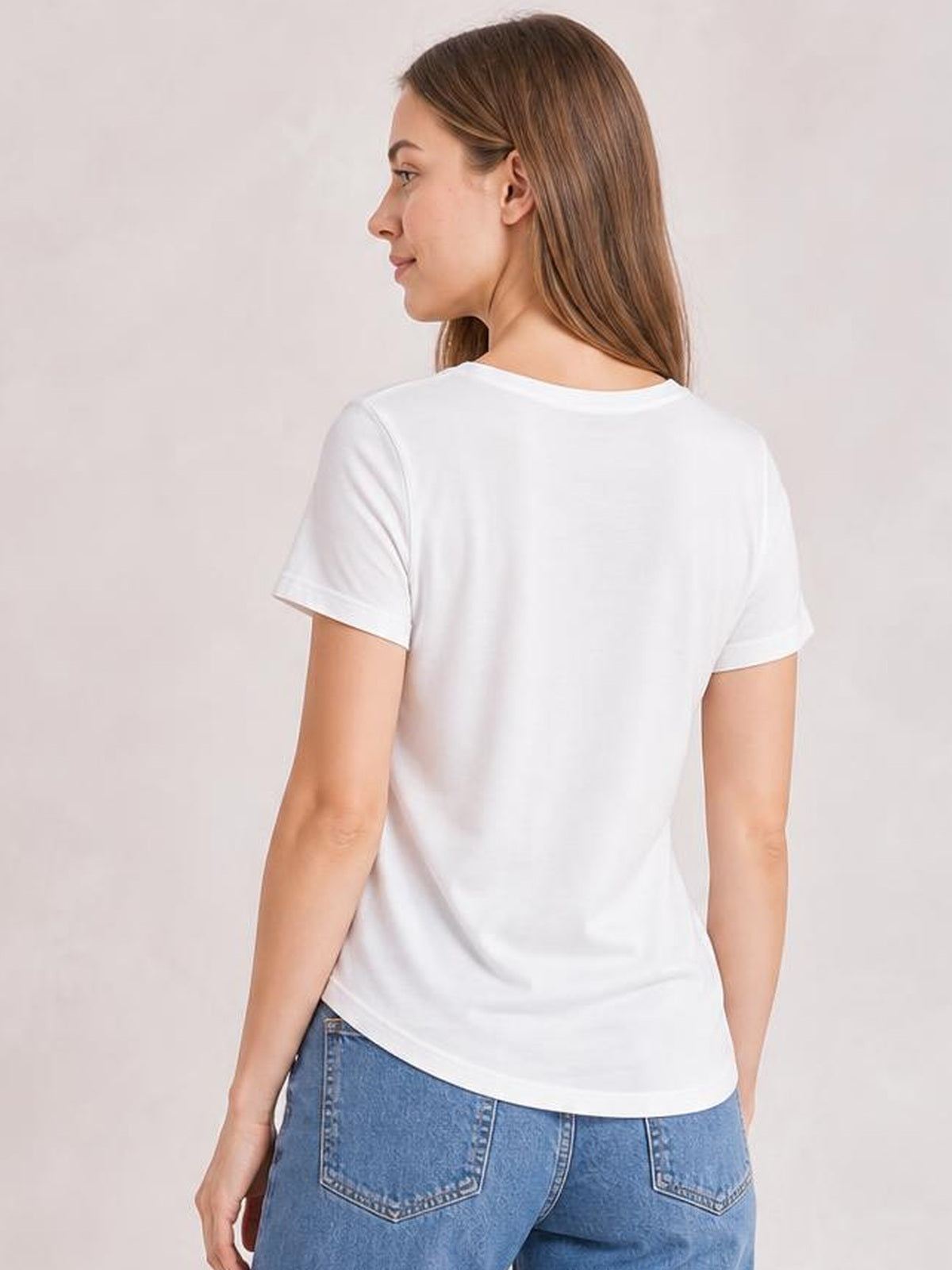 A model wears a white US Flag round-neck short-sleeve T-shirt with a relaxed silhouette, smooth construction, and gently curved hem, shown from the back.