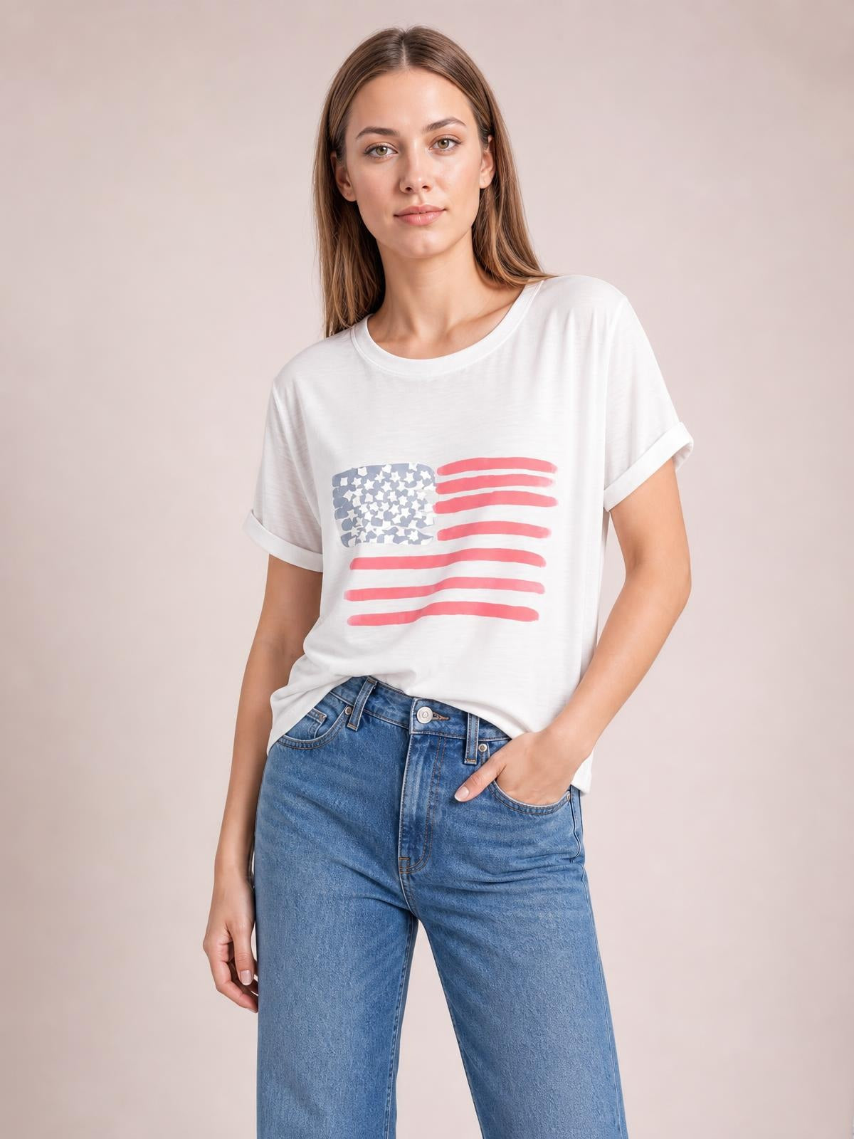 Model poses with one hand in her jeans pocket, wearing a white round-neck short-sleeve T-shirt with a red, white, and blue US flag graphic.