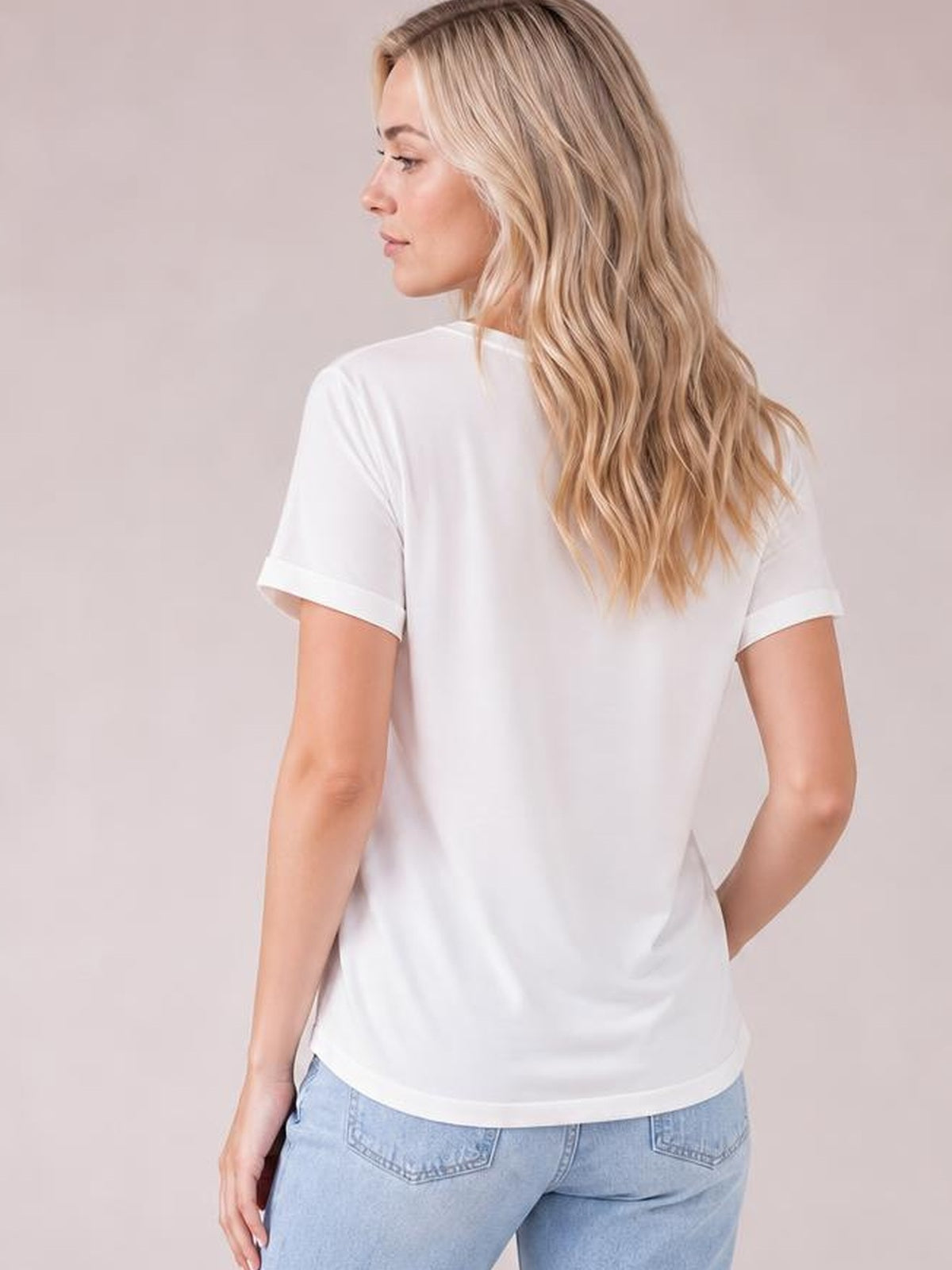 Model shown from behind wears a white crew neck T-shirt with short sleeves, a relaxed straight silhouette, and a clean hem while resting one hand on her hip.