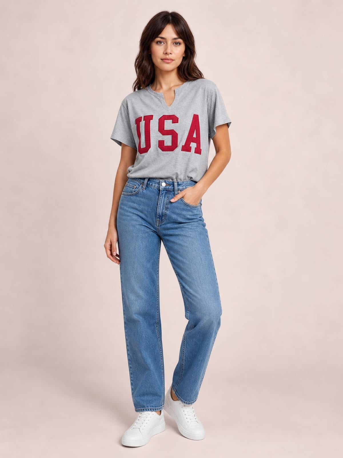 Model wears a gray USA notched short sleeve T-shirt with red lettering, a relaxed straight silhouette, and a V-notch neckline while standing casually.