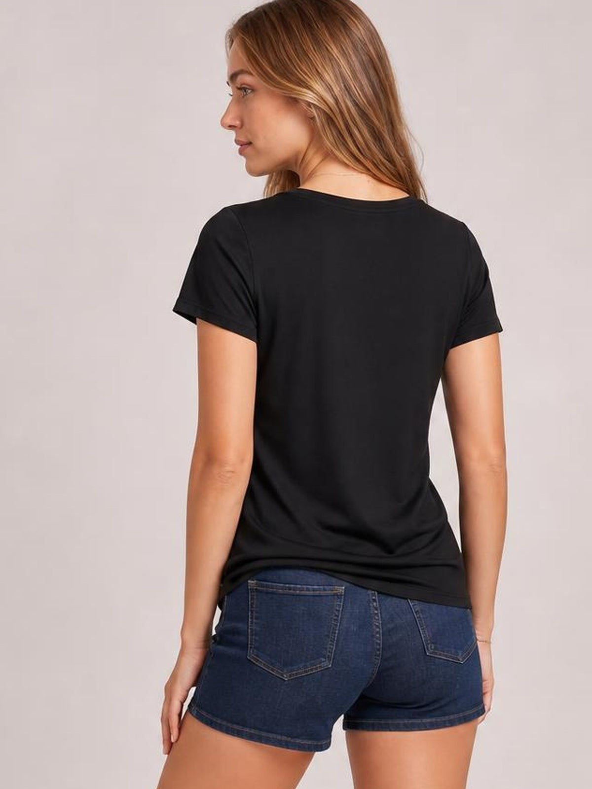 Model looks over her shoulder wearing a black opaque USA rhinestone round-neck T-shirt with short sleeves, a relaxed straight silhouette, and clean back construction.