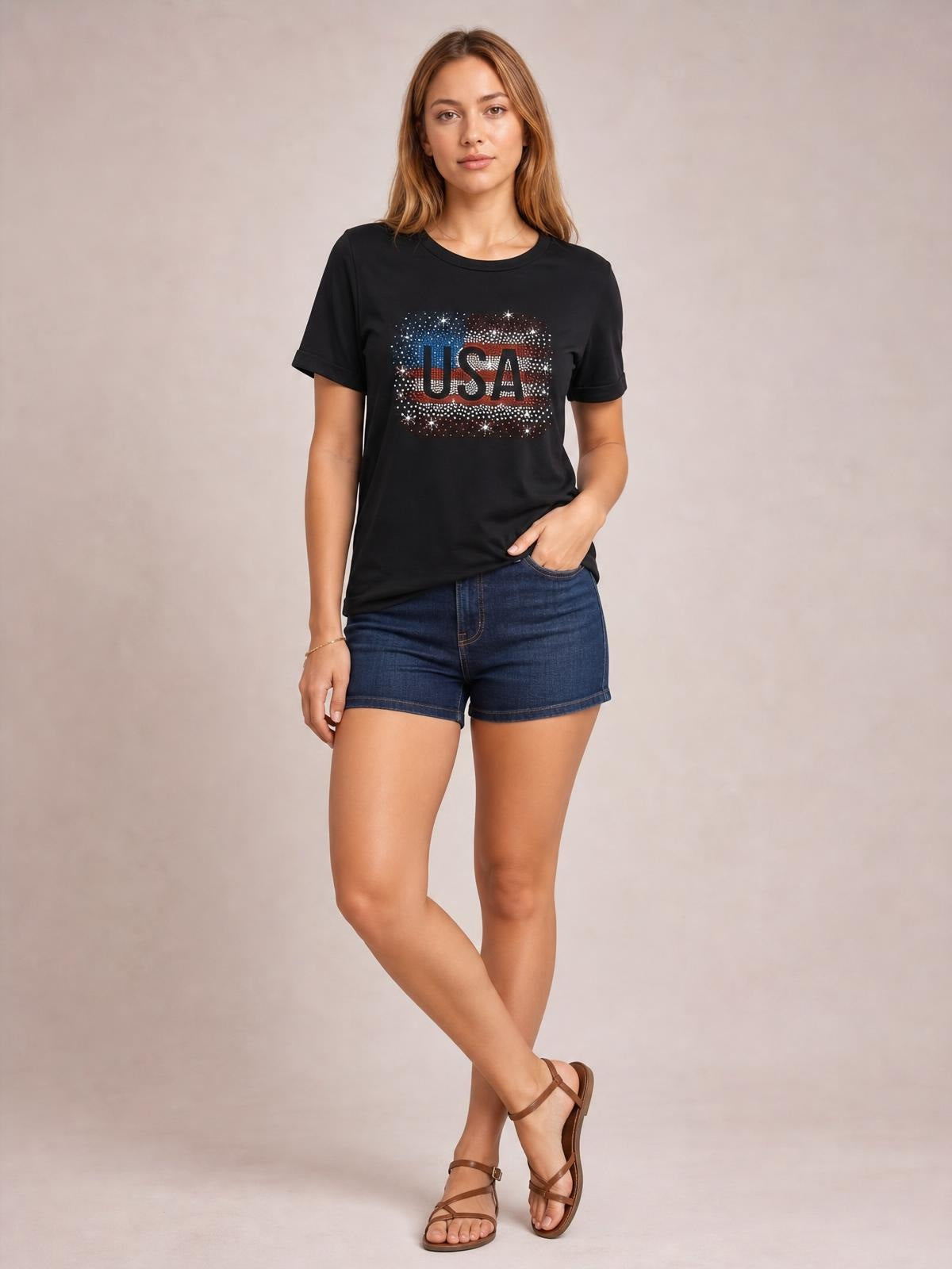 Model poses in a black USA rhinestone round-neck short-sleeve T-shirt with a relaxed silhouette and rolled sleeve cuffs.
