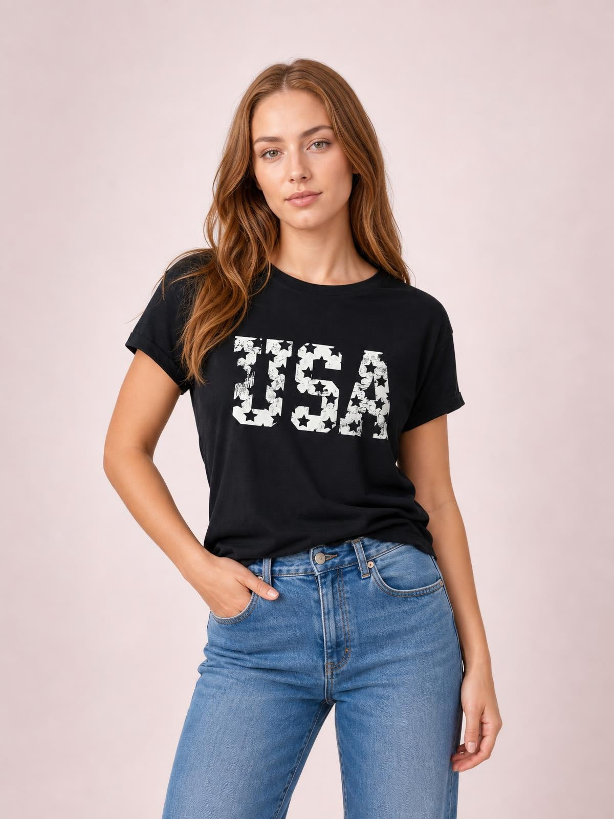 A model poses in a black USA round neck short sleeve T-shirt with a relaxed silhouette, rolled sleeve hems, and bold white star-print lettering.