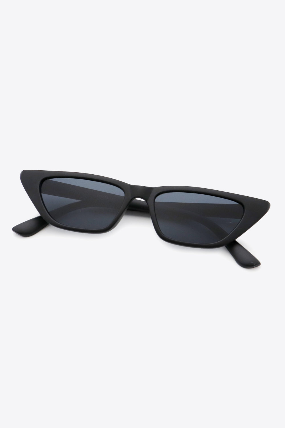 Black polycarbonate cat-eye sunglasses feature a sleek angular frame, sharply tapered outer corners, dark lenses, and extended temples in a front-facing view.