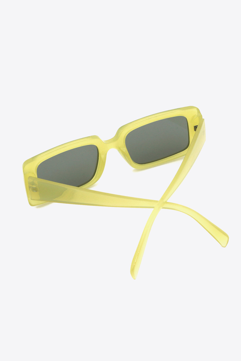 Yellow-green polycarbonate rectangle sunglasses with softly squared frames, dark-tinted lenses, and open temples crossed beneath the frame.